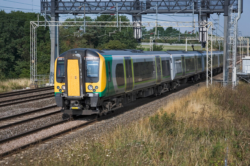 350121, unidentified up working, between Roade & Ashton 
 Under some clear blue skies and in warm late summer sunshine 350121 works an unidentified up London Midland service between Roade and Ashton in Northamptonshire. Unfortunately, I have not got my calculations quite right with the sun haveing just round too far at my chosen spot. 
 Keywords: 350121 between Roade & Ashton