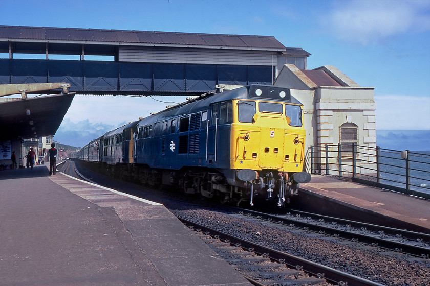 31255 & 31273, 09.25 Birmingham New Street-Paignton (1V68), Dawlish station 
 A service typical of what good old BR could lay on for a summer Saturday was the 1V68 Birmingham New Street to Paignton service seen here passing through Dawlish station in this case hauled by 31255 and 31273. However, another contemporary source has this down as the 1B56 10.25 Paddington to Paignton. Now, far be it from me to challenge the latter assumption but double-headed Class 31s and a long rake of Mk. 1s were far less common from London as they would have been from Birmingham. If any of my readers can corroborate any of this information please do contact me. It's a shame that I am on the wrong side for the sun but double-headed Class 31s on the sea wall at Dawlish is pretty special either way! 
 Keywords: 31255 31273 09.25 Birmingham New Street-Paignton 1V68 Dawlish Station