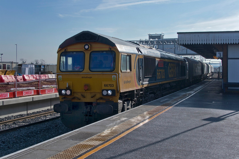 66703, 09.47 Neasden Charrington-Bardon Hill (6M32, 3E), Wellingborough station 
 Whilst I really like photographing in the winter months, when it is actually sunny, it does create issues as outlined in this particular image. With the sun being so low in the sky the shadows are deep and very dark. Photoshop needs to be put to good use in order to take control of the extreme contrast to lighten the shadows and yet still maintain nice tones in the highlights, particularly in the all-important skyscape. 66703 'Doncaster PSB 1981-2002' leads the 6M32 09.47 Neasden to Bardon Hill empty stone train through a transitional Wellingborough station. This particular train caught me unawares as up until its passage the slow lines had been out of use. The first that I was aware that it was imminent was the automated announcement stating that 'the next train at platform three is not scheduled to stop' and warning me to 'stand back from the platform edge'! 
 Keywords: 66703 09.47 Neasden Charrington-Bardon Hill 6M32 Wellingborough station Doncaster PSB 1981-2002 empty stone train