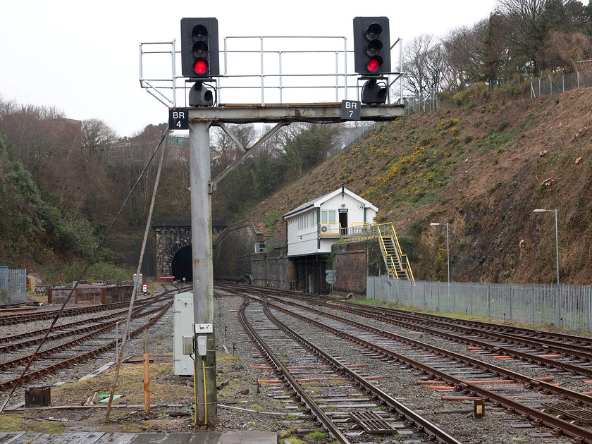 Bangor Signal Box (LNWR, 1923) 
 This is the second time that I have taken a picture of Bangor's LNWR 1923 signal box. The first time I visited in 1981 I was able to get a lot closer and a frontage shot resulted, see.... https://www.ontheupfast.com/p/21936chg/30035069794/x37-bangor-signal-box-lnw-1923. No chance of this now with all areas around it totally off-limits. This is the remaining box of the two that were situated at either end of the station with this one being formally known as Bangor Number 2. It is built in an interesting position half into the bank behind with the iron frame base sitting atop a substantial brick structure incorporated in the retaining wall. 
 Keywords: Bangor Signal Box