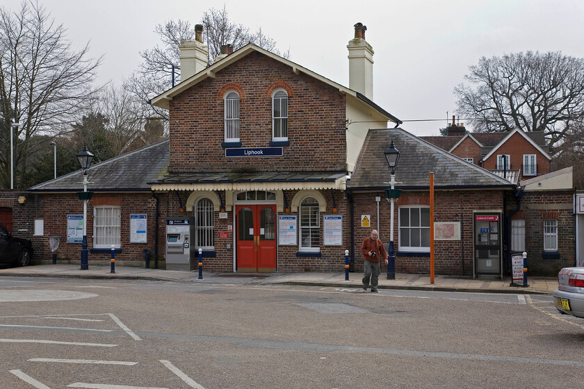 Frontage, Liphook station 
 The attractive station building at Liphook is seen from the station car park. The station was opened on 1st January 1859 with the building being constructed a little later and is a typical style for the London and South Western Railway. Having 'coped' the station Andy emerges walking back towards the car. 
 Keywords: Liphook station