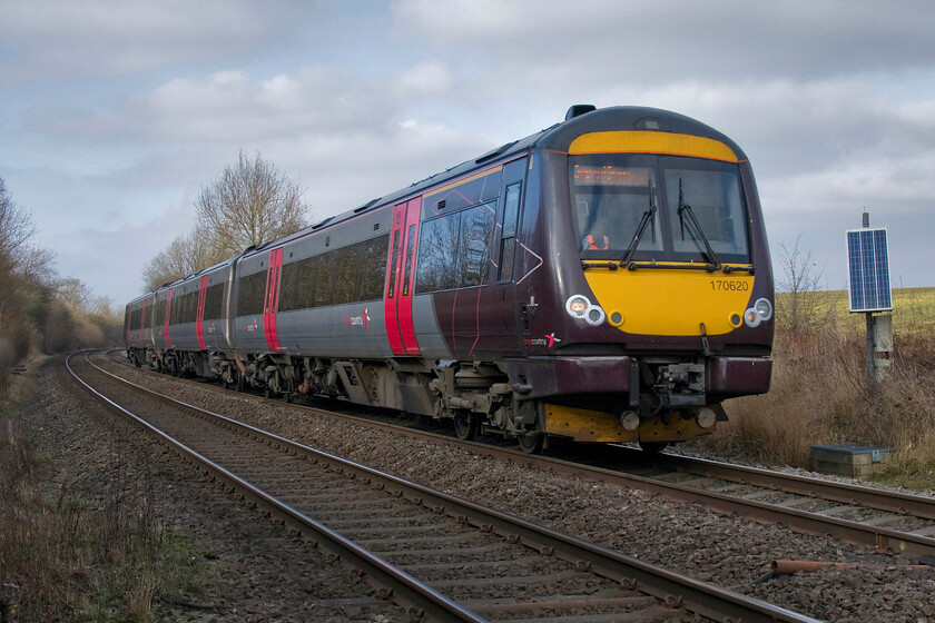 170620, XC 12.22 Birmingham New Street-Stansted Airport (1L40, 11E), Wymondham crossing 
 Catching some very welcome afternoon winter sunshine at the remote Wymondham level crossing the 12.22 Birmingham to Stansted Airport CrossCountry service passes at speed worked by 170620. This is a super spot to enjoy the passing of trains in the company of a very friendly crossing keeper who occupies the small crossing box. As the passage of trains is greater in number than road users the gates are kept closed to the latter as a matter of course. 
 Keywords: 170620 12.22 Birmingham New Street-Stansted Airport 1L40 Wymondham crossing Cross Country