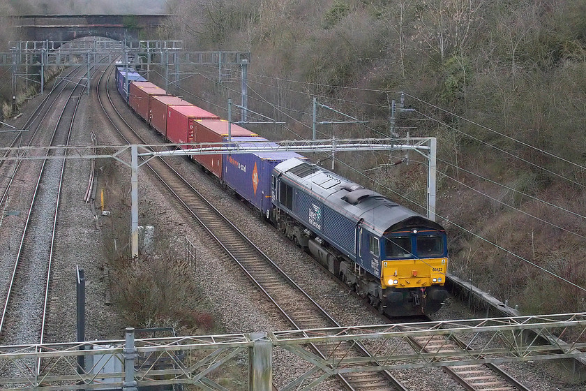 66423, 13.09 DIRFT-Purfleet (4L48), A508 road bridge, Roade 
 66423 brings the SuO 13.09 (or time thereabouts) Daventry International Railfreight Terminal to Purfleet Freightliner train. This 4L48 working is seen about to pass under the A508 main road bridge in the village of Roade having just emerged from the depths of Roade Cutting. I have a virtually identical photograph of the same working being hauled by the same locomotive at the same location but in early summer, see .....https://www.ontheupfast.com/p/21936chg/29048920604/x66423-13-09-dirft-purfleet-4l48 
 Keywords: 66423 13.09 DIRFT-Purfleet 4L48 A508 road bridge, Roade