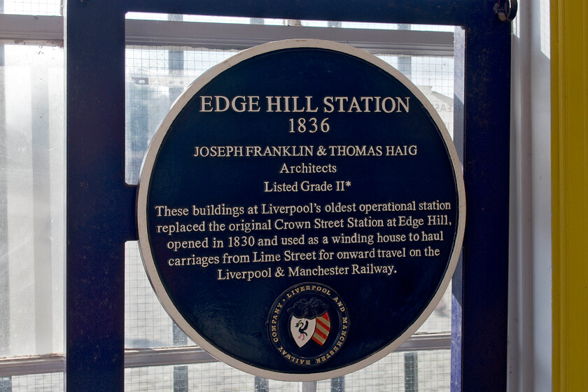 Plaque, Edge Hill station 
 The blue plaque inside the ticket office at Edge Hill station proclaiming its historical importance. It reveals that the original western terminus of the Liverpool to Manchester railway at Crown Street was only open for some five years. Crown Street was simply too far from the city centre hence why Lime Street was opened being linked to Edge Hill via the present-day steeply graded mixture of gloomy deep cuttings and tunnels. 
 Keywords: Plaque Edge Hill station.