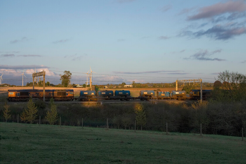 66752 & 66701, 11.52 King's Norton OT Plant-Bletchley (3J01, 5L), Roade Hill 
 A second 'grab' photograph of the 11.52 King's Norton to Bletchley (via much of the Midlands!) RHTT passes just south of Roade. As can be seen, the full length of the train almost fits in the gap but any further left and it would have been in complete shade! Leading the 3JO1 is 66701 with 66752 'The Hoosier State' bringing up the rear. The latter locomotive is one of the initial batch of twenty-one ordered by GBRf that arrived on UK soil ten years ago. Unusually, this example was named before it left EMDs Muncie facility in the USA for UK soil. 
 Keywords: 66752 66701 11.52 King's Norton OT Plant-Bletchley 3J01 Roade Hill GBRf RHTT