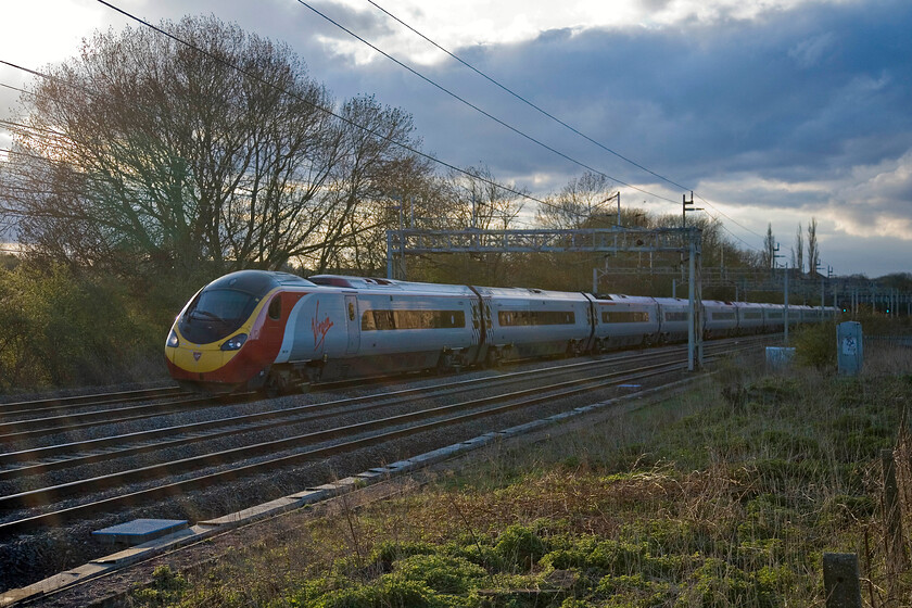 390124, VT 17.48 Liverpool Lime Street-London Euston, Roade 
 Breaking all the photographic rules and with the sun creating a very artistic refraction effect within the lens 390124 passes Roade working the 17.48 Liverpool Lime Street to Euston service. 
 Keywords: 390124 17.48 Liverpool Lime Street-London Euston, Roade Virgin West Coast Pendolino