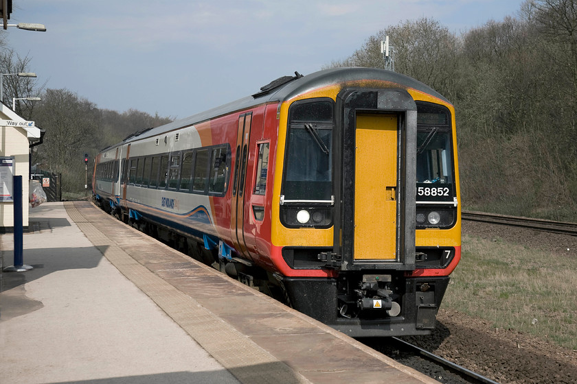 158852, EM 09.57 Norwich-Liverpool Lime Street (1R78), Dore station 
 158852 passes Drore's single platform in the spring sunshine working the 09.57 Norwich to Liverpool Lime Street. It is now on the trans-Pennine Hope Valley route leaving behind the Midland line that heads south towards Derby that can be seen to the right. Dore station is a shadow of itself with it once boasting four platforms that served both the Midland tracks and the doubled Hope Valley route. Plans are under discussion to expand the station once again with route enhancements to improve both freight and passenger train capacity. 
 Keywords: 158852 09.57 Norwich-Liverpool Lime Street 1R78 Dore station