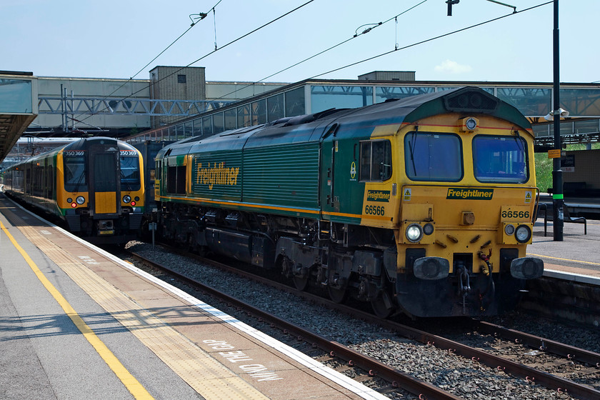 350369, LM 14.47 Milton Keynes Central-London Euston (2K32, 6L) & 66566, 09.25 Southampton FLT-Garston FLT (6M66), Milton Keynes station 
 350369 sits at Milton Keynes Central station waiting to leave with the 14.47 to London Euston. Meanwhile, 66566 heads north with the 09.25 Southampton to Gaston Freightliner. Not the finest shot due to the very bright summer lighting and being the wrong side for the sun. 
 Keywords: 350369 2K32 66566 09.25 Southampton FLT-Garston FLT 6M66 Milton Keynes station