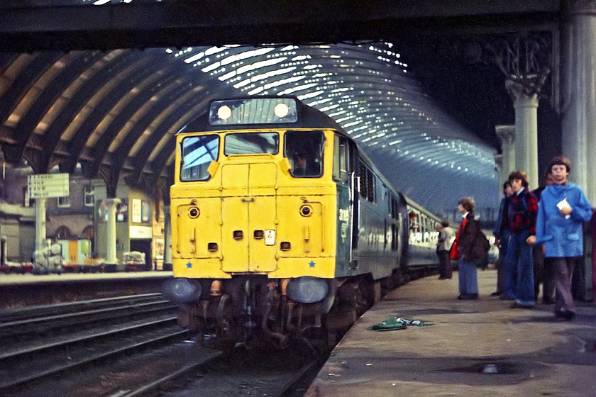 31195, unidentified down working, York station 
 31195 stands under York's impressive trainshed at the head of an unidentified down working. The spotters, including my school friend and part-time spotter Robin (in the red and black donkey jacket), look on as I crouch down to take another of my trademark low-angle shots!