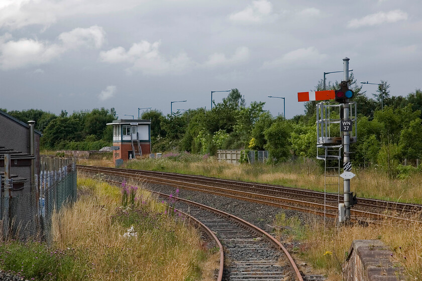 Wigton signal box (BR, 1957), up starter & loading bay 
 My last visit to Wigton was in 1985 when I managed to get much closer to the signal box for a better photograph. Today, the box still stands and the mechanical signalling is still in full operation. The box is a standard British Railways design and dates from 1957. The short spur into the loading bay does not appear to have seen traffic for some time!

NB on my 2024 re-visit I took a very similar image, see.... https://www.ontheupfast.com/p/21936chg/30056636681/wigton-signal-box-br-1957-up-starter 
 Keywords: Wigton signal box BR, 1957 up starter & loading bay