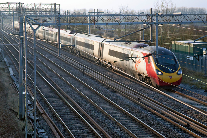 Class 390, VT 07.20 London Euston-Manchester (1H09, 5L), Hungate End SP784465 
 With the rising sun reflecting off its side, a Virgin Pendolino heads north with the 07.20 London Euston to Manchester Piccadilly. It is difficult getting good spots for early morning trains on the lower WCML in sunny conditions as is illustrated here! This situation is exacerbated in winter when the sun is that much lower! 
 Keywords: Class 390 Pendolino 1H09 Hungate End SP784465