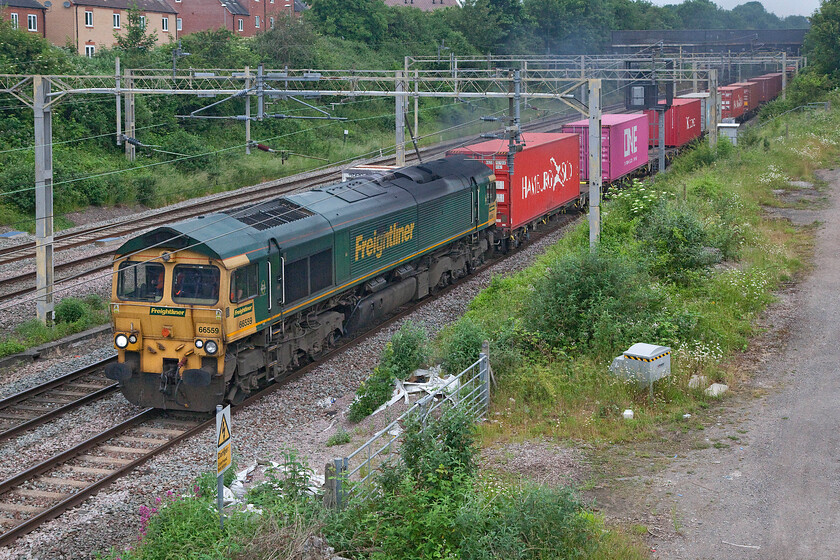 66559, 03.25 Garston-London Gateway (4L52, 3E), site of Roade station 
 On a dull and grey June morning (like so many this summer!) 66559 leads the 4L52 03.25 Garston to London Gateway past the site of Roade station. Coming up to its twentieth birthday this member of the class was emitting a lot of visual exhaust and, as can be seen here, it is looking a little tatty. One wonders if some extra heavy attention is needed rather like in the good old days of BR when locomotives had complete overhauls more resembling a nut and bolt rebuild. 
 Keywords: 66559 03.25 Garston-London Gateway 4L52 site of Roade station Freightliner