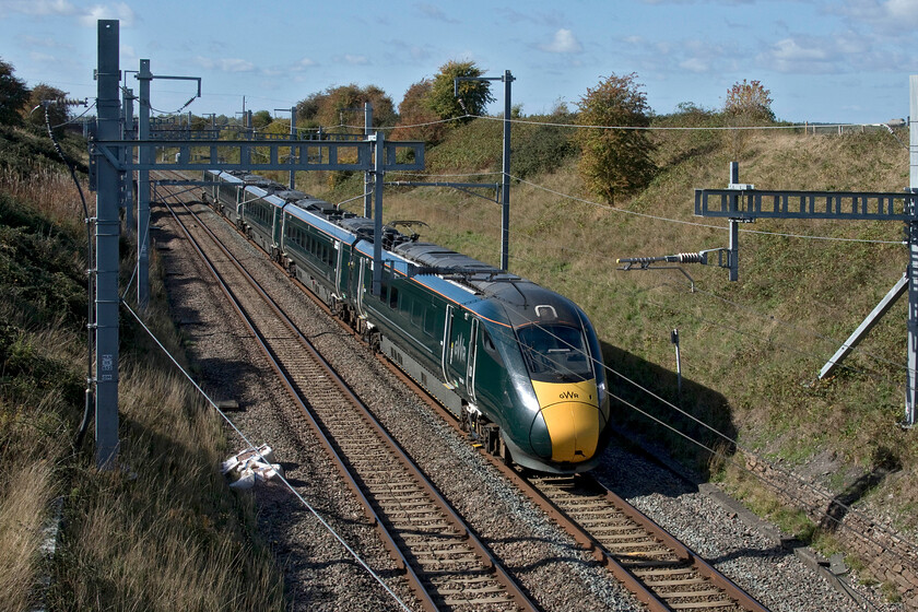 800028, GW 11.59 Cheltenham Spa-London Paddington (1L74, 3L), Bourton SU232875 
 800028 works the 11.59 Cheltenham to Paddington 1L74 service past Bourton between Swindon and Didcot. This used to be an easy bridge from which to take photographs in either direction but Network Rail has fitted some huge parapet extensions (anti-suicide barriers) and the brambles are really going rampant climbing the fencing at either end. So, my small step ladder was needed to get this position; it used to be so easy! 
 Keywords: 800028 11.59 Cheltenham Spa-London Paddington 1L74 Bourton SU232875 GWR IET