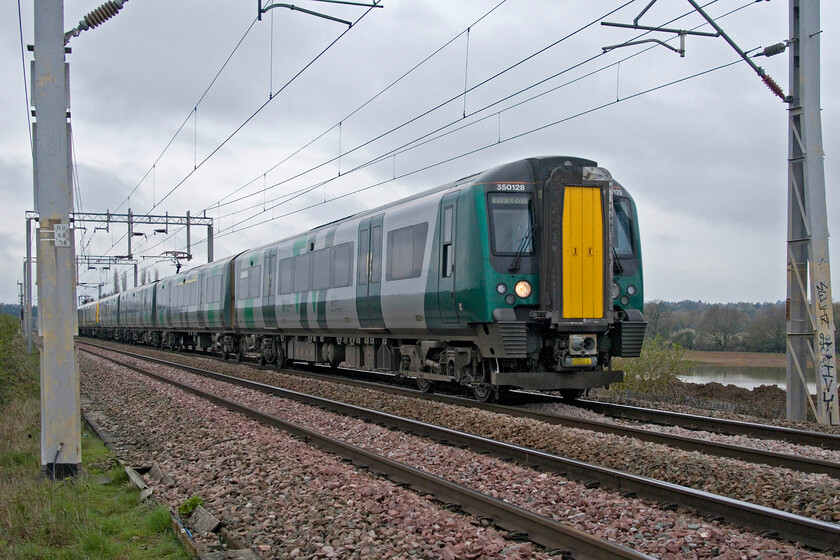 350128, LN 08.36 Birmingham New Street-London Euston (1Y16, 3L), Wilson's Crossing 
 The 08.36 Birmingham New Street to Euston service approaches Northampton from the north at Wilsons Crossing. Notice the huge new artificially created lake behind the train being constructed as part of the huge housing and road developments in this previously essentially rural area enjoyed by locals and dog walkers as well as wildlife; a blight affecting huge parts of the country. 
 Keywords: 350128 08.36 Birmingham New Street-London Euston 1Y16 Wilson's Crossing London Northwestern Desiro