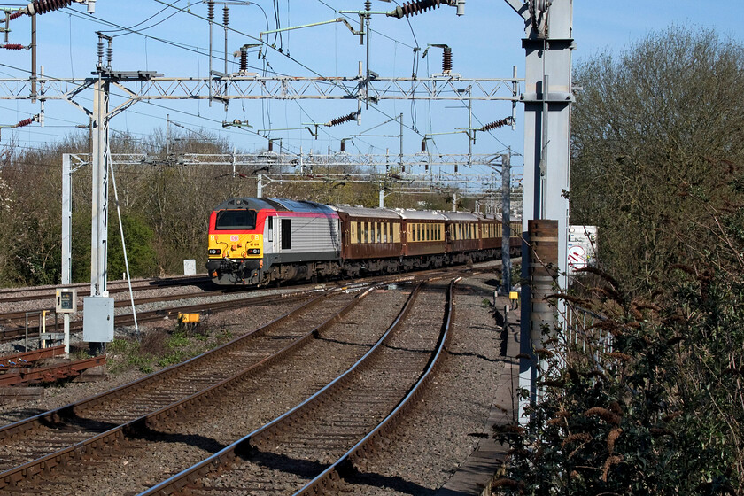 67014, 07.52 London Victoria-Runcorn (1Z50, 2L), Spenlows footbridge 
 I'm not a particular fan of 'going-away' shots but when the sun is out and in the right direction and the subject matter is interesting then I'll give them a go! Here, taken from Spenlows bridge just north of Bletchley 67014 brings up the rear of the 1Z50 07.52 Victoria to Runcorn Nagex carrying racegoers to the Aintree Grand National. Luckily the train was going relatively slowly so I was able to compose this reasonable photograph as it headed towards Milton Keynes. 
 Keywords: 67014 07.52 London Victoria-Runcorn 1Z50 Spenlows footbridge