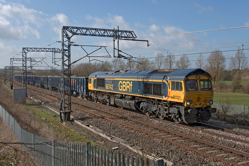 66742, 09.15 Tunstead Sidings-Northampton Castle Yard (6B92, 8E), Bird's Lane bridge 
 The 6B92 09.15 Tunstead to Northampton Castle Yard is a train that I have rarely photographed. Even more unusually, I have never seen it off-route as seen here passing Bird's Lane bridge (near Bugbrooke) on the Weedon loop heading south of its destination as far as Bletchley. 66742 'ABP Port of Immingham Centenary 1912-2012' is leading the train that, once it arrives at Bletchley, will run round the train to then head north again to Northampton. All these shenanigans were due to the closure of Crick tunnel near DIRFT for much-needed drainage work. It's nice to see a smart GBRf locomotive with a matching set of equally smart JNA-T open wagons that seem to have evaded the worst ravages of the graffiti vandals. 
 Keywords: 66742 09.15 Tunstead Sidings-Northampton Castle Yard 6B92 Bird's Lane bridge GBRf GB Railfreight ABP Port of Immingham Centenary 1912-2012