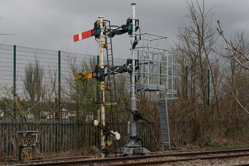 Dudding Hill 12 signals old and new, Gladstone Park TQ225857 
 Remarkable survivors number 2.....

The two and a half-mile of freight only line that joins Dudding Hill Junction to Acton Wells Junctions still operates as absolute block, has semaphore signals and has a total of four signal boxes in operation, quite an incredible survivor. Not only that but, as can be seen from this image, Network Rail has embarked on an upgrade of the line, not to destroy all the old signalling but to replace the gantries and arms with new ones! Taken through the fence in Gladstone Park the DH12 signal post is seen with the new one recently installed, complete with arms' cover by the requisite black bags with Xs on them. The S & T team have had to improvise with the covers as no standard ones are available for mechanical arms as per the hoods placed over new coloured lights. Hence, they have appeared to have used bin bags with white gaffer tape! All the old signalling was being replaced. The question that I have is, who today will they have got to make the new enamel arms? 
 Keywords: Dudding Hill 12 signals old and new Gladstone Park TQ225857