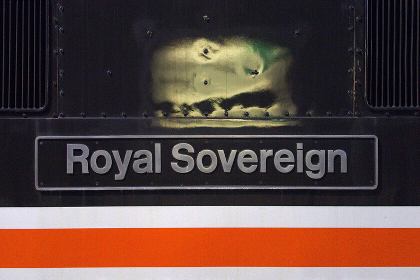 Nameplate, 87002, outward leg of The Capital's Scot, 06.56 London Euston-Edinburgh Waverley (1Z86, 1E), Milton Keynes Central station 
 LSL of Crewe has done a fine job recreating the InterCity Executive livery on 87002 'Royal Sovereign' including its superb nameplate as seen here whilst it pauses at Milton Keynes. The Class 87 was hauling the first mainline charter of the year (as far as I am aware) leaving Euston at 06.56 and heading for Edinburgh. The LSL charter appeared to be well loaded despite the time of year an it being a weekday especially as it only gave the punters just over two hours in Edinburgh before heading home south but on the ECML this time to King's Cross. 
 Keywords: 87002 The Capital's Scot 06.56 London Euston-Edinburgh Waverley 1Z86 Milton Keynes Central station InterCity Roayl Sovereign LSL