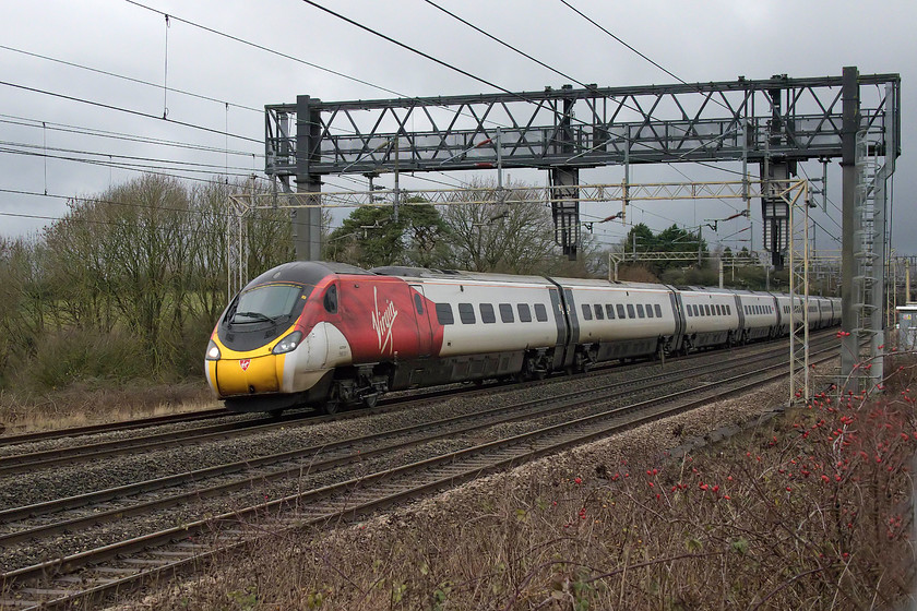 390011, VT 12.47 Wolverhampton-London Euston (1B26, 4E), between Roade & Ashton 
 Withe the rain leaden cloud arriving from the north west, 390011 'City of Lichfield' forms the 12.47 Wolverhampton to Euston. It is seen passing between Roade and Ashton in Northamptonshire. I had come out with no wet weather protection so was looking anxiously at the approaching cloud! 
 Keywords: 390011 12.47 Wolverhampton-London Euston 1B26 between Roade & Ashton