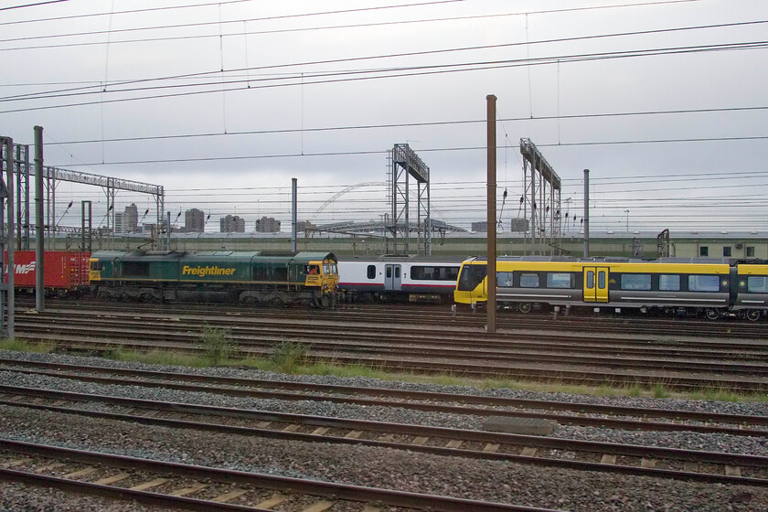 66565, 05.54 Trafford Park-Felixstowe North (4L44, 31E), Class 321, stored & 777032, awaiting delivery, Wembley Yard 
 New and old stand side by side in Wembley Yard with a Freightliner service about to pass between them! To the right is a new Merseyrail, 777032, that is awaiting onward movement to the northwest. 66565 is leading Freightliner's 4L44 05.54 Trafford Park to Felixstowe service. Finally, a stored former Great Eastern Class 321 hides towards the back awaiting its fate; whatever that may be. 
 Keywords: 66565 05.54 Trafford Park-Felixstowe North 4L44 Class 321 777032 awaiting delivery Wembley Yard Freightliner Merseyrail