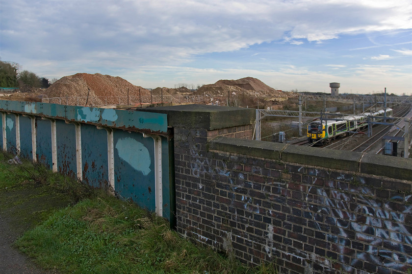 Class 350, unidentified down working, site of Roade station 
 An alternative viewpoint at the site of Roade's former station. Adopting a wide-angle reveals the footbridge that used to afford locals access to the station from both sides of the village that straddles the WCML. The huge mounds in the background ar all that remains of the former Pianoforte factory that has been demolished over the past year to make way for a vast new housing estate that will be built on the site. The unidentified Class 350 is about to pass under the bridge with an unidentified northbound London Midland service, 
 Keywords: Class 350 unidentified down working site of Roade station London Midland Desiro