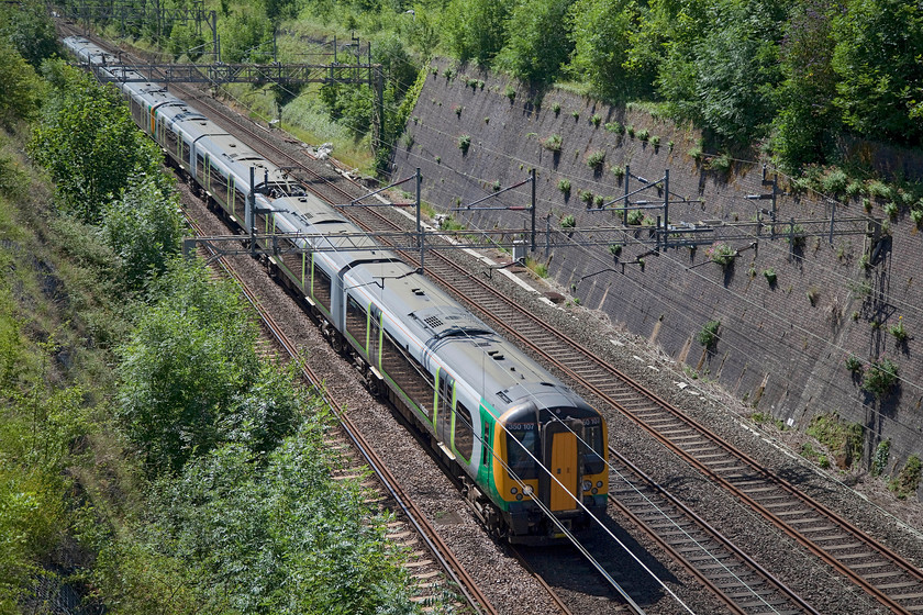 350107 & 350123, LM 09.54 Birmingham New Street-Northampton (2N33, RT), Roade Cutting 
 350107 and 350123 were both part of the initial deliveries of the class 350/1 Desiros that commenced in 2005. They entered service in a neutral and unbranded grey colour with doomed Central and Silverlink Trains. Only when London Midland took over these two franchises did they emerge in their familiar green livery. The two units are seen passing through Roade Cutting working the 09.54 Euston to Birmingham New Street. 
 Keywords: 350107 350123 2N33 Roade Cutting