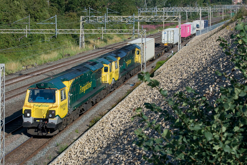 70005 & 70004, 06.14 Crewe Basford Hall-Southampton MCT (4O14, 27L), Ashton Road bridge 
 With the Great Western route, through Oxford shut again the diversion of freight that uses that route was once again taking place along the WCML. However, unlike the last closure that lasted some months due to the collapse of the Thames crossing at Nuneham this time it is only for this week for works in and around Oxford station. The diverted 4O14 06.14 Crewe Basford Hall to Southampton passes just south of Roade with consecutively numbered 70005 and 70004 leading. Only the leading Class 70 appeared to be under power. 
 Keywords: 70005 70004 06.14 Crewe Basford Hall-Southampton MCT 4O14 Ashton Road bridge