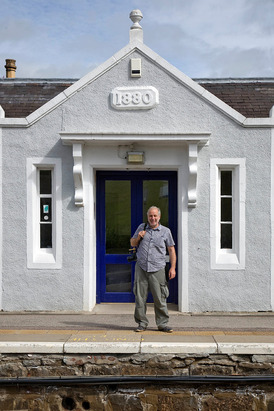 Andy, Insch station 
 Andy is a little older than me but not quite that old! He stands on the lovely Insch station under the somewhat elaborate pediment on the front of the station building that now houses the Insch Connection Museum that unfortunately, on the day of our visit, was closed. It was about now, on consulting my signalling atlas, that I realised that we had missed Kennethmont signal box some miles back west. As we were on a bit of a mission to get to Dundee I had to forget that one but realised that I would not be likely to ever get back to visit it again as resignalling of the entire Aberdeen to Inverness line is imminent. 
 Keywords: Andy Insch station