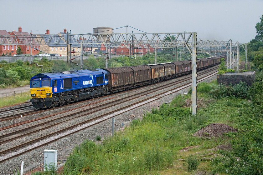 66142, 11.33 Dollands Moor-DIRFT (6M45, 62L), site of Roade station 
 In weak afternoon lighting 66142 'Maritime Intermodel Three' leads the daily 6M45 11.33 Dollands Moor to Daventry loaded bottled water train past Roade. This train (and its balancing southbound empty wagon service) are dependable daily workings on this section of the WCML and it is unusual to see either of them running late, an hour in this case due to problems in the Wembley area earlier on and then signalling problems in Milton Keynes. 
 Keywords: 66142 11.33 Dollands Moor-DIRFT 6M45 site of Roade station Maritime Intermodel Three