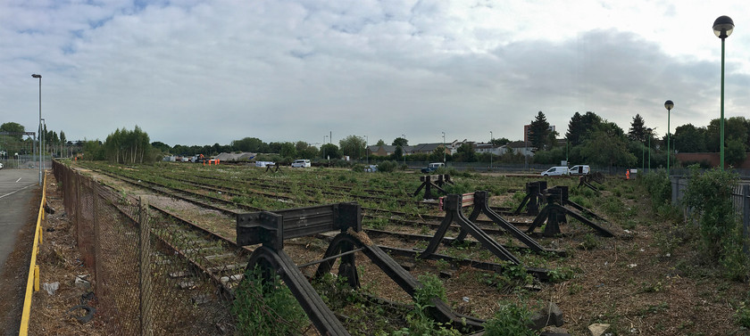 Northampton Castle Yard 
 Over the past few months or so, Northampton's largely abandoned Castle Yard has been cleared of foliage that had gradually enveloped it over the last twenty years or so. This was in preparation for a change of use extending the station car park that, despite its ugly second storey being added a few years ago, is wholly inadequate; or is it? As a result of the COVID-19 pandemic, the concept of the daily commute to London to the office has been turned on its head. One wonders with the resultant recession if the traditional commuter rush will ever return as it was, meaning that a huge car park at stations like Northampton will not be required? This panoramic view of the yard shows the extensive tracks exposed now uncovered from the forest of trees that had taken over. Whilst the bottom of the yard has still to be cleared work will soon begin to remove the track hoping that it may be good enough to be donated to heritage lines perhaps? (Taken on my iPhone in panoramic mode.) 
 Keywords: Northampton Castle yard