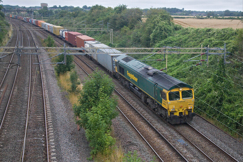 66515, 05.20 Crewe Basford Hall-London Gateway (4L52, 2E), Victoria bridge 
 After a week or so of fine and hot summer weather, it has taken a turn for the worst with cloudy and overcast conditions prevailing. 66615 leads the 4L52 05.20 Crewe Basford Hall to London Gateway past a grey Victoria bridge just south of Roade. 
 Keywords: 66515 05.20 Crewe Basford Hall-London Gateway 4L52 Victoria bridge Freightliner