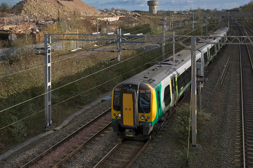 350117, LM 13.49 London Euston-Birmingham New Street (1W15), site of Roade station 
 350117 passes Roade working the 13.49 Euston to Birmingham New Street London Midland service. Notice the huge amount of work taking place in the background. The remains of the former Pianoforte factory has been demolished to make way for an extensive new housing estate that will have a pretty major impact on my home village. 
 Keywords: 350117 13.49 London Euston-Birmingham New Street 1W15 site of Roade station London Midland Desiro