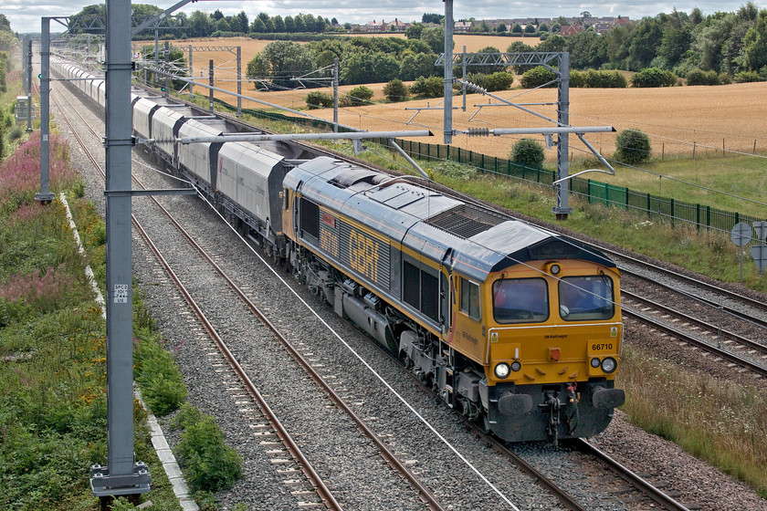 66710, 10.35 Bletchley Cemex-Peak Forest Cemex (6H10, 8L), Irchester SP927667 
 Taken totally against the sun 66710 'Phil Packer BRIT' brings the 6H10 10.35 Bletchley Cemex to Peak Forest empty stone wagons past Irchester. It is working north on the down slow line that, with the up slow still not in use, is bi-directional between Kettering and Bedford. Notice the dust being thrown up from the train emanating from the fresh ballast. 
 Keywords: 66710 10.35 Bletchley Cemex-Peak Forest Cemex 6H10 Irchester SP927667 GBRf Phil Packer BRIT