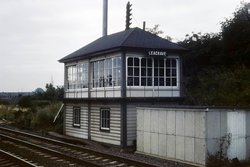 Leagrave signal box (Midland, date not known) 
 After the lovely weather the previous day, it has returned to type with dull and overcast conditions! With a new electrification mast emerging from behind its hipped roof, Leagrave signal box is seen. Being of timber construction and of this design it can only be a Midland box but, unfortunately, I do not have the date of its construction. 
 Keywords: Leagrave signal box