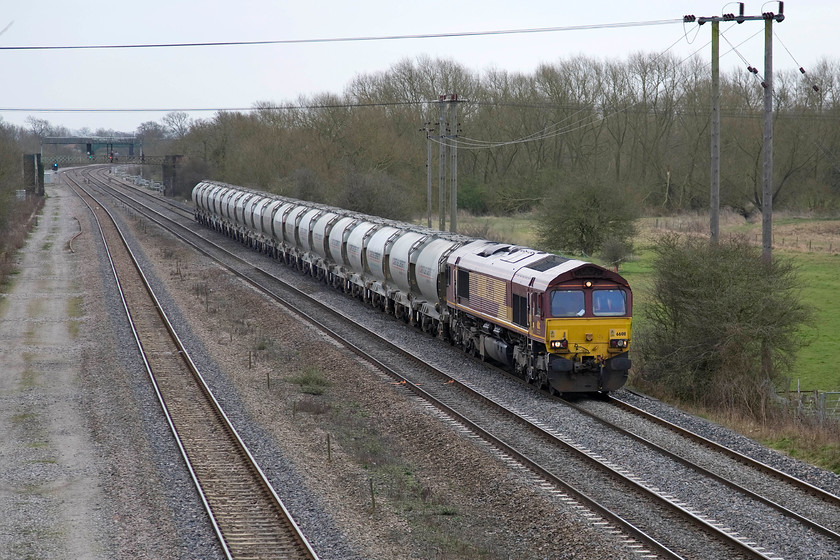 66011, 10.03 St. Pancras Churchyard Sidings-Ketton Ward Sidings (6F93), Station Road bridge Burton Latimer 
 A regular freight flow on the Midland Mainline is the 6F93 empty cement wagons from St. Pancras Churchyard sidings to Ketton cement works just west of Stamford. Unfortunately, this train has to go the extra distance via Leicester and Syston Junction rather than direct via Cobry and Manton Junction as there is no connecting spur from that line to access the eastbound line. 66011 leads the train as it trundles along the down fast line at Burton Latimer between Kettering and Wellingborough. This view is set to change in the coming few years as the second slow or relief line is to be reinstalled and then the line is to be electrified with initial preparations now underway in certain places. 
 Keywords: 66011 10.03 St. Pancras Churchyard Sidings-Ketton Ward Sidings 6F93 Station Road bridge Burton Latimer