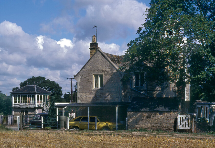 Former station building and signal box, Uffington 
 The former Uffington and Barnock station building is seen with the signal box in the background. The station was opened in 1846 by the Midland Railway on the former Syston and Peterborough Railways route. The station was not particularly well located for either the villages of Uffington or Barnock, as was often the case back in the early years of railway mania. This factor was one that probably precipitated its relatively early closure on 01.09.52. The building still survives as a private residence. Notice the rather conspicuously coloured Renault 20 under the car part identified from its Renault 30 bigger brother by its wheel covers and single headlights. Always a rather underwhelming offering from Renault it was not a great sales success but when was the last time that you saw one of these on the road? 
 Keywords: Station building and signal box Uffington