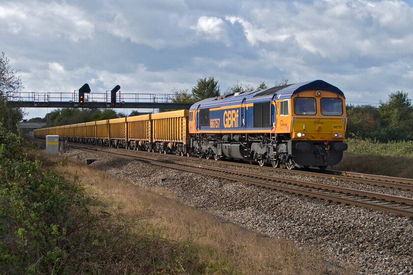 66757, 11.56 Westbury-Cliffe Hill Stud Farm (6M40), South Marston foot crossing SU193869 
 66757 leads the 11.56 Westbury to Cliffe Hill on the Isle of Grain in Kent with the locomotive catching a burst of October sunshine past a soon to be closed foot crossing at South Marston near Swindon. The empty wagons are going to the Kent virtual quarry to collect gravel to be returned to Westbury for use by the infrastructure teams. 
 Keywords: 66757 11.56 Westbury-Cliffe Hill Stud Farm 6M40 South Marston foot crossing SU193869