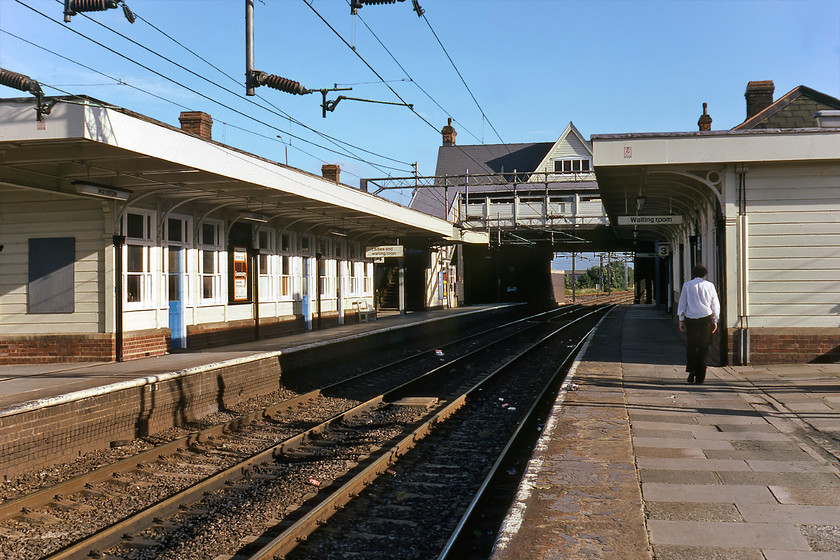 Slow lines, looking South, Wolverton station 
 Little did I know when I visited Wolverton station back in August 1980 that I would be living some ten miles away forty years later! Graham walks up platform three of the former LN&WR station dating from 1881 with the waiting rooms, footbridge and the elevated station building in view. Over the coming few years the station was completely remodelled as the old structures were deemed unsafe and not fit for purpose. Platform three is the down slow line with four the up slow, a situation that remains the same today. However, this is the only similarity as everything in this view has been wiped away. The closest present-day view I have is to be found at.... https://www.ontheupfast.com/p/21936chg/28936787604/x66502-07-50-felixstowe-north-lawley 
 Keywords: Slow lines looking South Wolverton station