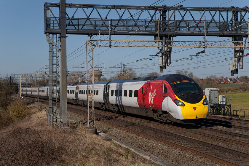 390011, VT 11.07 Wolverhampton-London Euston (1B13, 29L), Roade Hill 
 Looking very smart in it new style Virgin branding, 390011 'City of Lichfield' races past Roade Hill on its way south forming the 11.07 Wolverhampton to London Euston. The original livery created an illusion that the Pendolinos had big windows as the amount of their bodyside that was in black was much greater. However, in this livery, the real size of the windows is clear, they are a lot smaller than you were led to believe. 
 Keywords: 390011 1B13 City of Lichfield Roade Hill