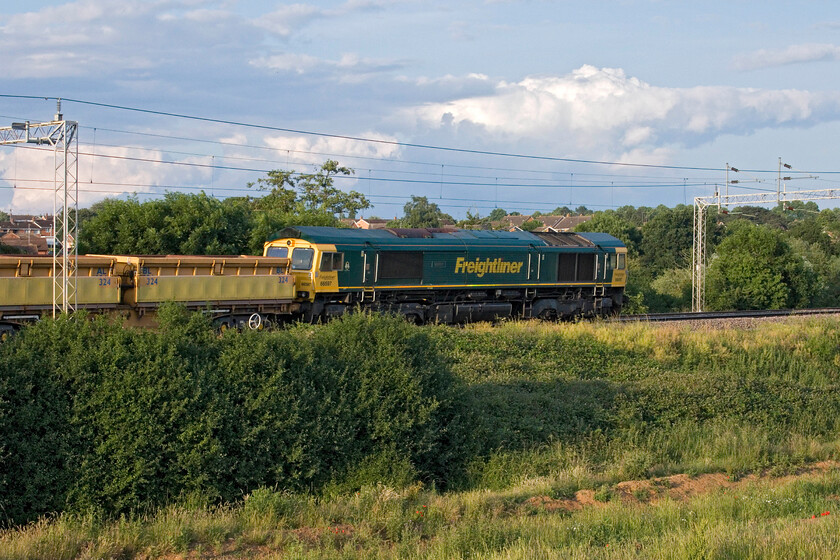 66597, 19.35 Bletchley flyover-Crewe Basford Hall (6Y62, 9L), Wilson's Crossing 
 Taken from an elevated position on a large bank built by the developers of the land in the foreground 66597 'Viridor' passes Wilson's crossing to the north of Northampton. It is at the rear of the regular 19.35 Bletchley flyover to Bescot Yard engineer's train that I had been waiting for watching its agonisingly slow progress northwards towards me! Normally the train would be fully illuminated by the evening sun at this spot but being the longest day it has actually round almost being north westerly! 
 Keywords: 66597 19.35 Bletchley flyover-Crewe Basford Hall 6Y62 Wilson's Crossing Freightliner Viridor