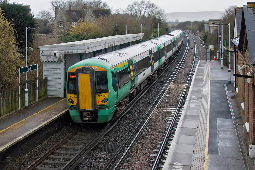 377103, SN 14.33 Ore-Brighton (1G37, 1E), Glynde station 
 377103 pauses at Glynde station in the pouring rain working the 14.33 Ore to Brighton. There were a couple of passengers on the station with nobody alighting from the train in this small and quiet village. There were few cars in the car park so it did not appear to be a particular favourite with the 9-5 commuters. 
 Keywords: 377103 14.33 Ore-Brighton 1G37 Glynde station