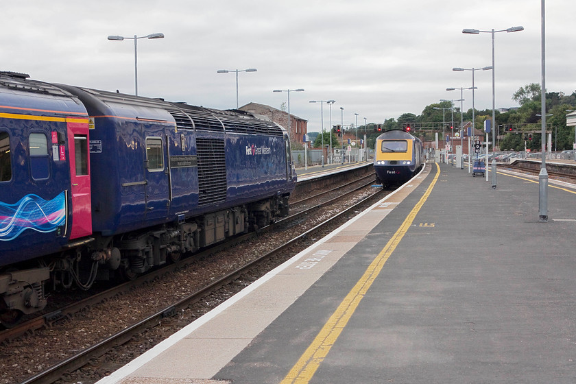 43087, GW 17.33 London Paddington-Paignton (1C91, 3E) & 43150, 19.34 Taunton-Laira TMD ECS (5C22), Exeter St. David's station 
 A meeting of HSTs at Exeter St. David's station. To the left 43087 '11 Explosive Ordnance Disposal Regiment Royal Logistics Corps' is at the rear of the 17.33 Paddington to Paignton. It is about to be overtaken by 43150 that is running non-stop through the station as the 5C22 19.34 Taunton to Laira ECS. This explains why I have taken the picture, what looks to be a little early. As the light was so poor I was already pushing the camera's ISO capacity somewhat and could not get a fast enough shutter speed to capture a non-stopper close up with no motion blur. 
 Keywords: 43087 1C91 43150 19.34 Taunton-Laira TMD ECS 5C22 Exeter St. Davids station