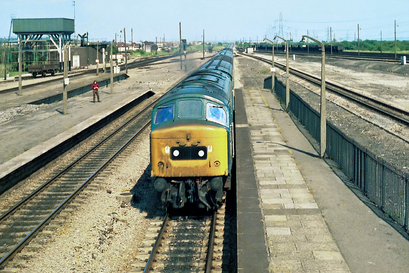 45016, unidentified down working, Severn Tunnel Junction station 
 This shot shows a little of the vast expanses that made up Severn Tunnel Junction yard. Even by this stage, much of the track had been removed but it was still a busy place and great source of cops! 45016 was not, however, a cop! With its head code panel now replaced with the domino style markers it races through Severn Tunnel Junction with a westward bound express. I suspect that this working would have originated from the north and travelled down via Birmingham New Street, Gloucester and then along the side of the Severn Estuary through to Chepstow. Notice in the background the substantial ex. GWR water tower and behind that the original sheds (86E) still standing.