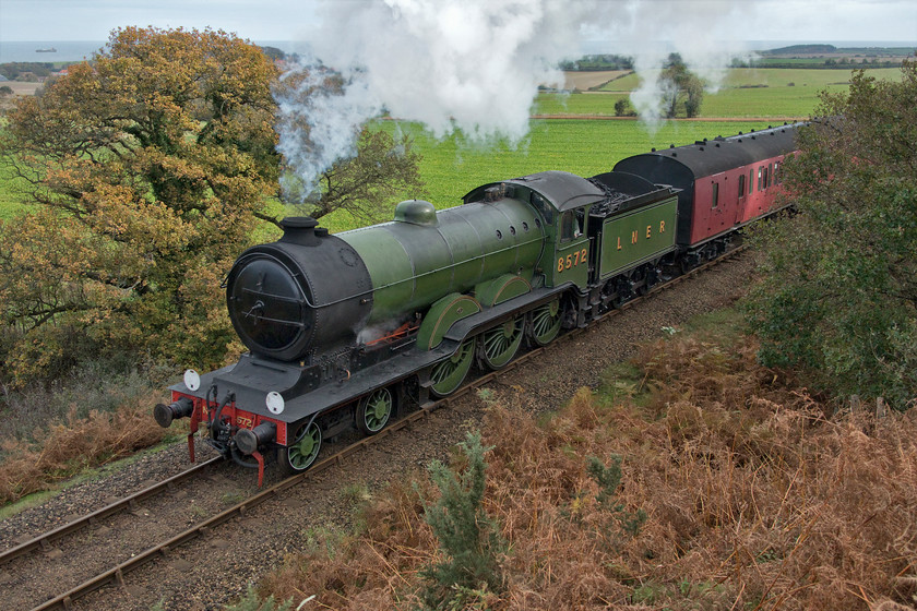 8572, 10.00 Sheringham-Holt, Kelling bank 
 Formally of Norwich shed (32A) former LNER 8572 makes its customary charge up Kelling bank with the 10.00 Sheringham to Holt North Norfolk Railway service. The autumn colours are looking good in this photograph with the bracken in the foreground turning its characteristic reddish-brown at the end of its growing season. Notice the North Sea at the top of the scene with the coaster making its way towards King's Lynn from Rotterdam according to the vessel-tracking app. on my 'phone.

There is an audio recording of this event at my YouTube site, see... https://youtu.be/ytOD_wqvG6k 
 Keywords: 8572 10.00 Sheringham-Holt Kelling bank LNER B12 4-6-0