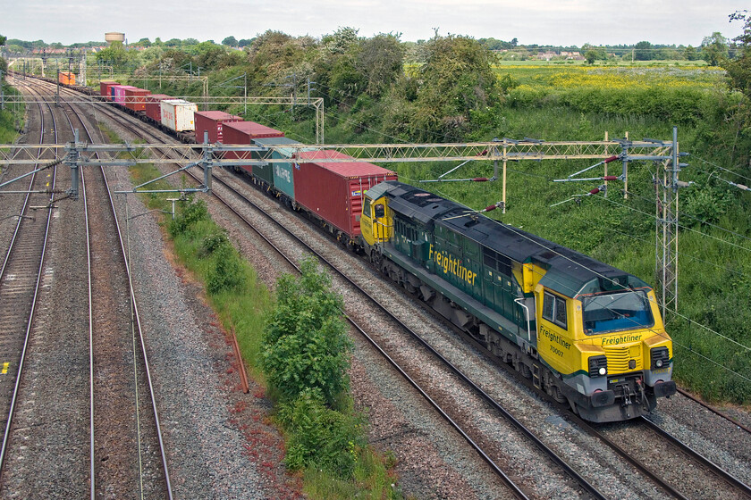 70007, 09.36 Crewe Basford Hall-Southampton MCT (4O49, 69L), Victoria bridge 
 Avoiding the sun by a few hundred metres, 70007 leads the diverted 09.36 Crewe Basford Hall to Southampton Freightliner service past Victoria bridge just south of Roade. By the end of the month, the number of these noisy and brash Class 70s passing on this route will drop significantly as they revert to their normal route via Banbury, Oxford and Didcot with the re-opening of the Nuneham bridge. 
 Keywords: 70007 09.36 Crewe Basford Hall-Southampton MCT 4O49 Victoria bridge Freightliner