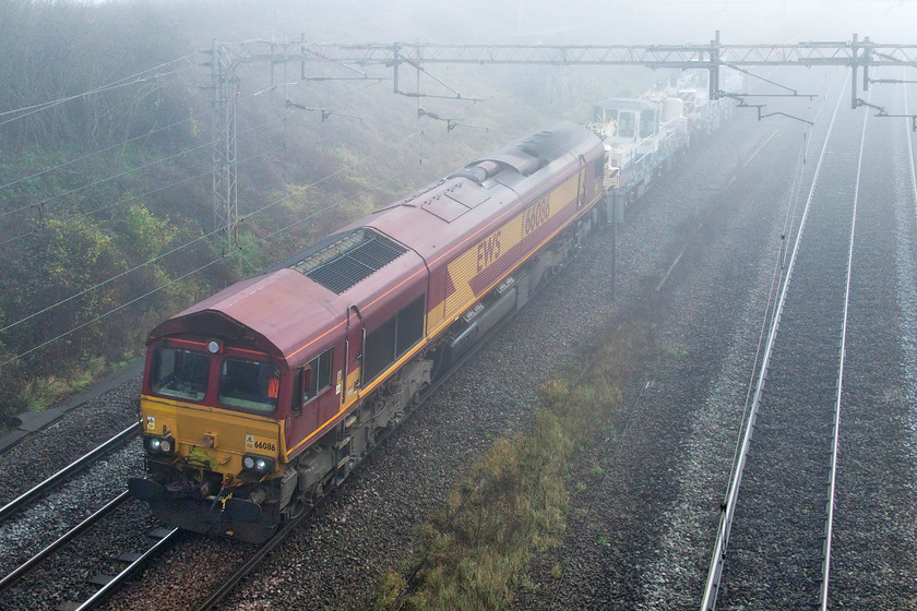 66086, 10.50 Watford South Junction-Bescot (7R02, 37E), Victoria bridge 
 66086 wears the EWS livery that it has since it entered service on the UK network twenty-one years ago. It is seen in the December fog passing Victoria bridge just south of Roade leading the 7R02 10.50 Watford South Junction to Bescot engineering train. This, and the previous train, had been involved in trackwork around Watford over the previous night. 
 Keywords: 66086 10.50 Watford South Junction-Bescot 7R02 Victoria bridge EWS