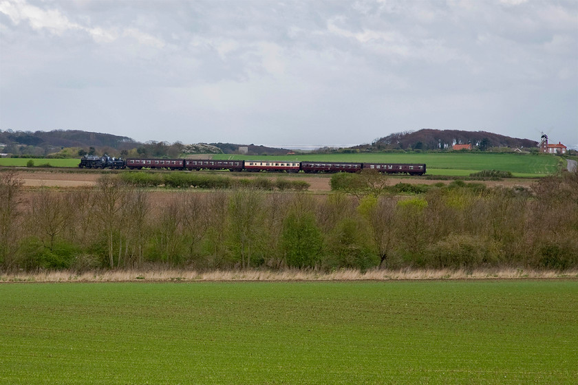 76034 (76084), 12.00 Sheringham-Holt, Sheringham Park TG132426 
 76084 leads the 12.00 Sheringham to Holt North Norfolk Railway service on the approach to Weybourne. The photograph is taken from the grounds of Sheringham Park during our walk. It appears that I have tipped the photograph slightly but the train is actually climbing at this point with the sea being level in the background. The grade II listed Weybourne windmill is seen to the extreme right of the photograph. 
 Keywords: 76034 12.00 Sheringham-Holt, Sheringham Park TG132426 Poppy Line NNR North Norfolk Railway British Railways Standard Class 4MT 76084