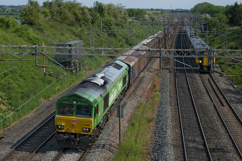 66004, 11.07 Dollands Moor-DIRFT (6M45, 2E) & 350241, LN 14.45 London Euston-Crewe (1U39, 6L), Victoria bridge 
 This is my first photograph of the one-off liveried DB 66004. It wears its green vinyls and statement 'I am a climate hero' but is it actually an official name? The Class 66 is part of an experiment to use various alternative fuels rather than diesel in an effort to reduce emissions with particular attention paid to CO2, see.... https://www.modernrailways.com/article/dbc-trials-eco-fuel-class-66 66004 is leading the daily 6M45 11.07 Dollands Moor to DIRFT bottled water train past Victoria bridge between Roade and Ashton. London Northwestern's 350241 is seen approaching on the down fast working the 14.45 Euston to Crewe service. 
 Keywords: 66004 11.07 Dollands Moor-DIRFT 6M45 350241 14.45 London Euston-Crewe 1U39 Victoria bridge I am a climate hero