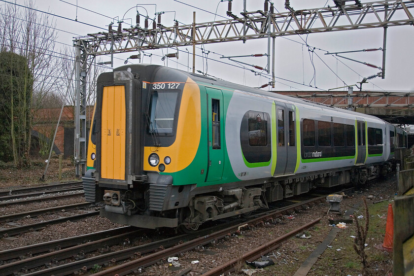 350127, LM 07.33 Birmingham New Street-London Euston, Northampton station car park 
 London Midland's 350127 leaves Northampton station (past the bridge) working the 07.33 Birmingham New Street to Euston service. Close observation of the first window of the leading carriage reveals a very neat reflection of the station's elevated station sign almost like I planned it! 
 Keywords: 350127 07.33 BNS-London Euston Northampton station car park London Midland Desiro