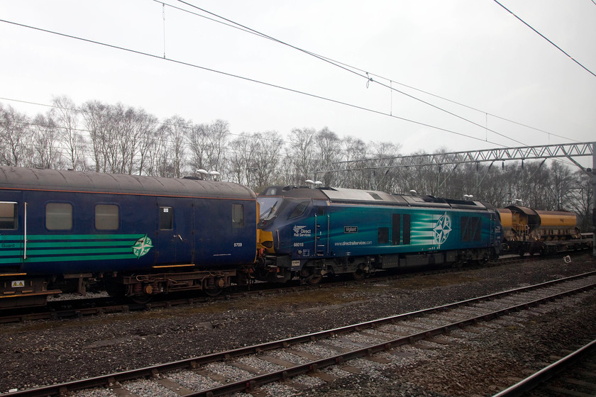 68018, stabled, Crewe LNWR 
 As we slowed for the stop at Crewe station 68018 'Vigilant' sits stabled at the LNWR yard. This is clearly a DRS locomotive with its distinctive compass logo as is the former 1974 Derby built BR Mk2 BSO now a DBSO 9709 that is still in use, mainly on the Cumbrian Coast. 
 Keywords: 68018, LNWR Crewe